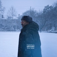 a man in a green jacket standing in the snow